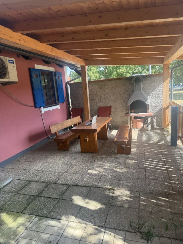 Pokrita terasa z zidanim žarom in leseno mizo